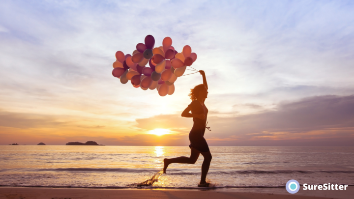Woman running along a beach with balloons in hand